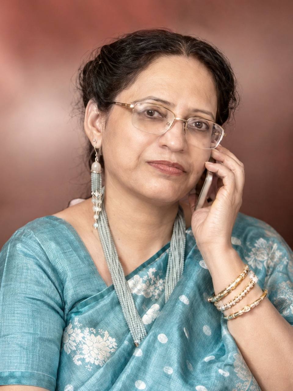 Portrait of Smita Sarkar in a teal sari holding a phone to her ear