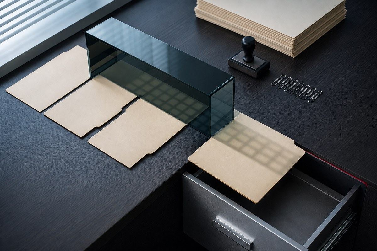Blank insurance claim folders diverted beneath a dark glass prism