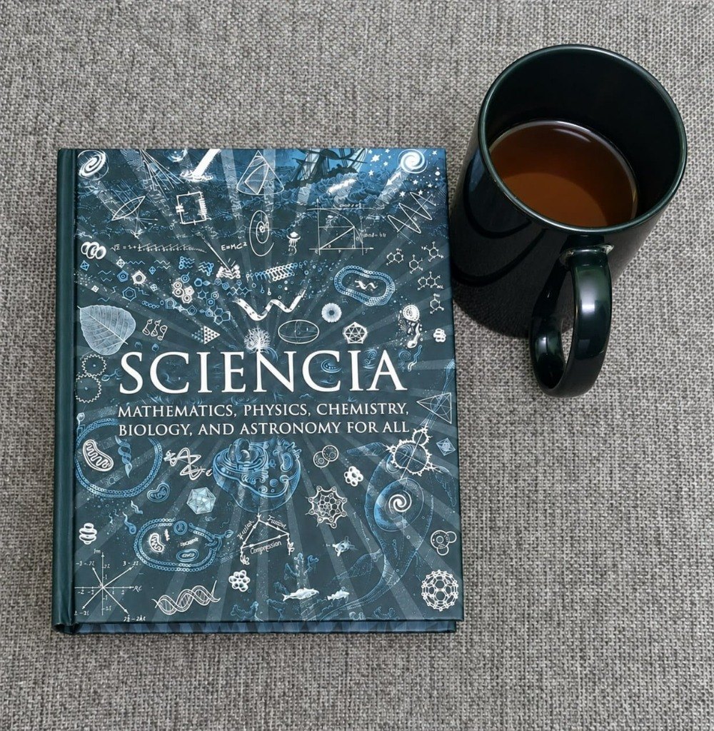 Sciencia beside a black mug, a science book bought for company during Durga Puja.
