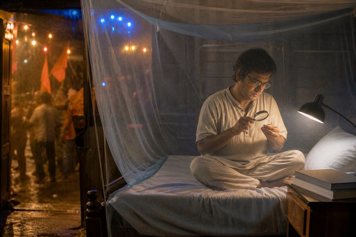 Bengali man examines a small object inside a mosquito net while spectacle glows outside