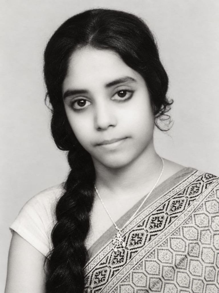 A vintage black-and-white portrait of the author's mother in her youth with a dark braid in a patterned sari
